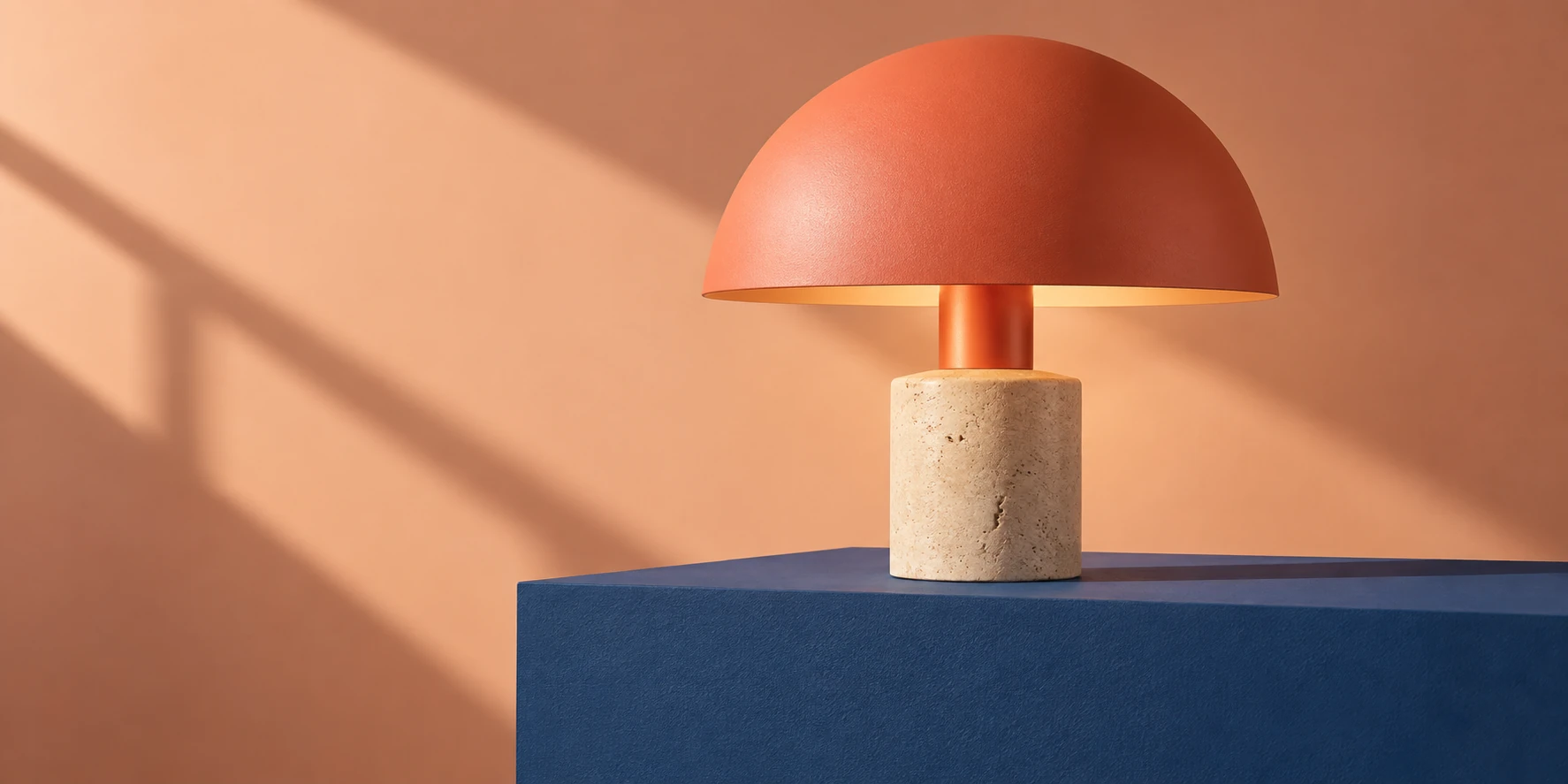 Coral table lamp on a cobalt plinth in a peach studio
